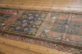 Vintage distressed Oushak runner's blush and bronze geometric border with time-softened blue field.