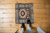 Antique Kurdish square rug mat with large palmette, viewed from above to illustrate its small scale.