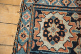 Corner view of an antique Kurdish bagface showing the geometric border and worn, hand-knotted edge.