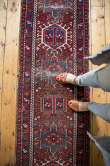 Vintage Karaja runner with geometric hook and latch medallions in cherry red and navy blue.