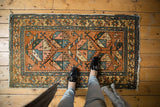 Vintage Heriz rug's geometric pattern in rainbow ribbon shades, showing mostly even wear.