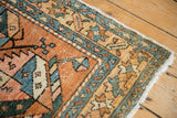 Heriz rug corner detail: pale red, ivory, and blue geometric patterns with even pile wear.