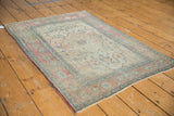 Antique Kerman rug detail: faded cochineal border, dark navy vinery, and worn ivory floral field.