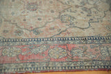 Faded cochineal red border, ivory field antique Kerman rug, navy vinery, mostly even wear.