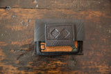 Embossed logo detail on the stitched dark brown leather flap of the handmade coin purse.