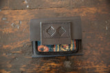 Embossed geometric logo on the stitched leather flap of the rug fragment coin purse.