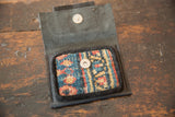Leather coin purse opened to show its colorful rug fragment lining and magnetic snap.