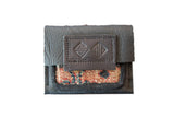 Dark leather coin purse featuring a colorful, geometric rug fragment and an embossed logo flap.