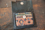 Interior of the leather coin purse showing the woven rug fragment pocket and metal snap.