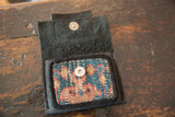 Interior view of the mini wallet, highlighting the metal snap and geometric rug fragment.