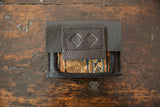 Pebbled brown leather flap with embossed logo on a woven rug fragment coin purse.