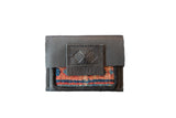 A black leather wallet featuring a textured rug fragment with rust, blue, and black stripes.