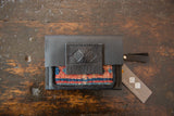 Black leather and rug wallet with debossed logo flap and Swag and Tassel brand tag.