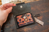 Open leather coin purse showing the vintage rug fragment interior pocket and metal snap.
