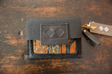 Dark pebbled leather wallet with colorful rug fragment and Swag and Tassel tag.