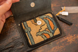 Open leather coin purse showing geometric beige, teal, orange rug fragment and magnetic snaps.
