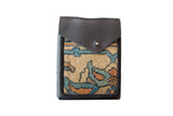 Rug fragment shoulder bag with a brown leather flap over a beige and blue floral pattern.