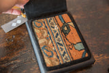 Textured hand-knotted rug fragment with terracotta and blue pattern, metal snap.
