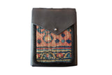 Handmade leather shoulder bag with a vibrant geometric hand-knotted rug fragment.