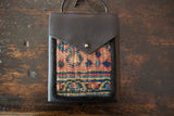 Unique rug fragment in the shoulder bag's lower section with muted geometric pattern.