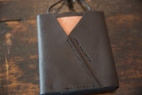 Detail of dark brown leather shoulder bag, light tan triangle, and Swag and Tassel imprint.