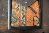 Detail of shoulder bag's vibrant orange and blue rug fragment panel.