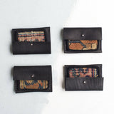 An assortment of black leather wallets displaying unique and colorful vintage rug fragment patterns.