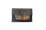 Dainty rug fragment wallet with dark leather flap and blue, tan geometric pattern.