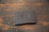 Embossed geometric logos on the dark brown textured leather wallet's front.