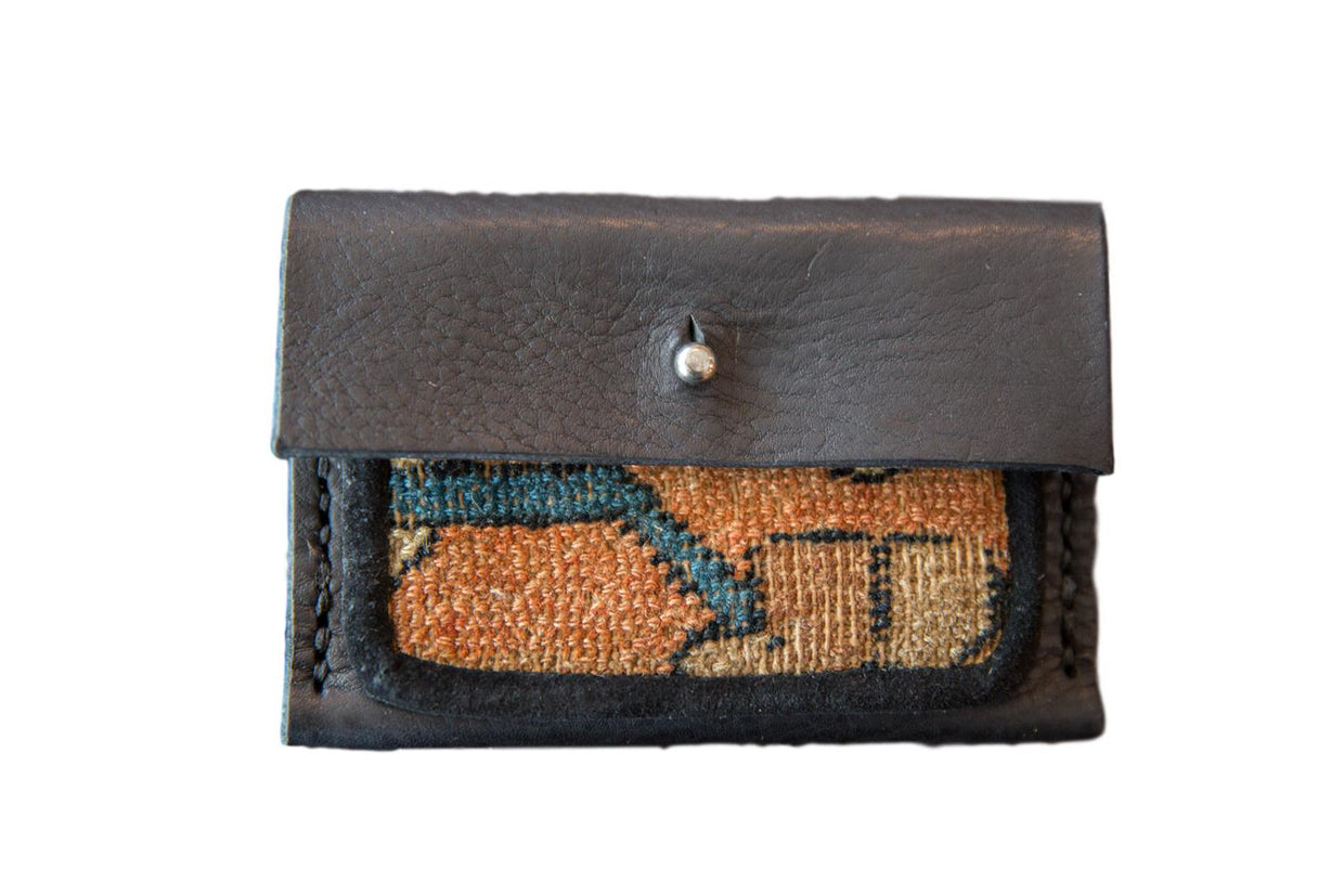 Dainty rug fragment wallet featuring dark leather, orange, blue, and tan woven textile.