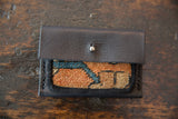 Textured close-up of the wallet's hand-woven rug fragment, featuring orange, teal, and beige patterns.
