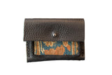 Dainty rug wallet of dark pebbled leather featuring a blue and orange geometric textile panel.