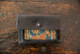 Textured black leather flap with silver snap on the rug fragment wallet.