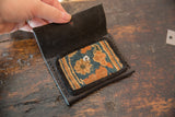 Black leather wallet opened to reveal the interior rug fragment pocket and snap closure.