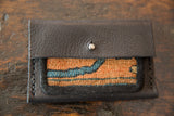 Dark leather flap with metal snap on Dainty Rug Fragment Wallet, orange and blue textile.