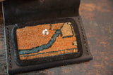 Hand-woven vintage rug fragment inset in wallet, showing orange, blue, and beige patterns.
