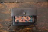 Dark brown pebbled leather flap with silver snap and woven rug fragment detail.