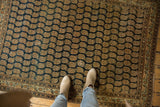Finely woven antique Haji Jalili Tabriz rug with repeating rust boteh on a dark navy field.