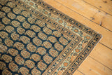 Antique Haji Jalili Tabriz rug corner: finely woven navy boteh, multi-hued border, and restored selvage.