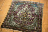 Angled overview of a square antique silk Kashan mat with a moody palette of eggplant and aqua.