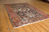 Vintage Karaja rug's detailed brick red border, navy blue field, fringe, and visible wear.