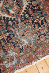 Worn vintage Karaja rug corner with brick red border, navy field, geometric blossoms, fringe.