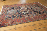 Intricate brick red main border and navy field of the vintage Karaja rug, showing wear.