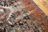 Vintage Karaja rug with geometric floral motifs, wear exposing foundation, navy, brick red, ivory.