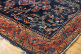 Vintage Lilihan rug corner, navy floral field, dusty raspberry border, gold wave pattern, light tatter.