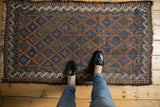 Antique Belouch rug corner with indigo multi-medallion field, wave and pawn borders.