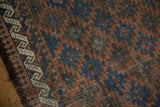 Antique Belouch rug detail: Reciprocating wave border and field patterns in indigo, terracotta, and brown.