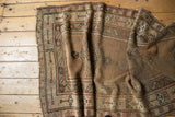 Vintage Caucasian runner with geometric trees border, faded field patterns, and exposed foundation.