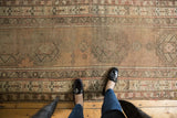 Vintage Caucasian runner showcasing geometric design, faded colors, and visible foundation beneath feet.