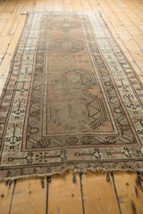 Vintage Caucasian runner with single medallion, geometric buds, and a timeworn blush-gold palette.